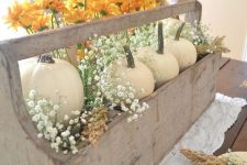 a vintage rustic Thanksgiving centerpiece of a wooden box with white pumpkins, orange blooms and baby’s breath
