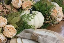 a vintage rustic Thanksgiving table with wooden chargers, burlap placemats, faux greenery, berries, peachy blooms and pumpkins