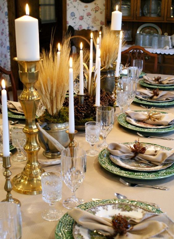 a vintage rustic Thanksgiving tablescape with printed plates, wheat, pinecones, gold candleholders and refined glasses
