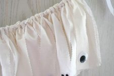 a white fabric strap garland with googly eyes for scary and chic decor at a white Halloween party