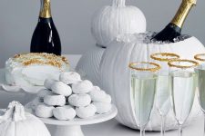 a white sweets table with white cookies, a cake, pumpkins, various ghost sweets and a white pumpkin drink cooler