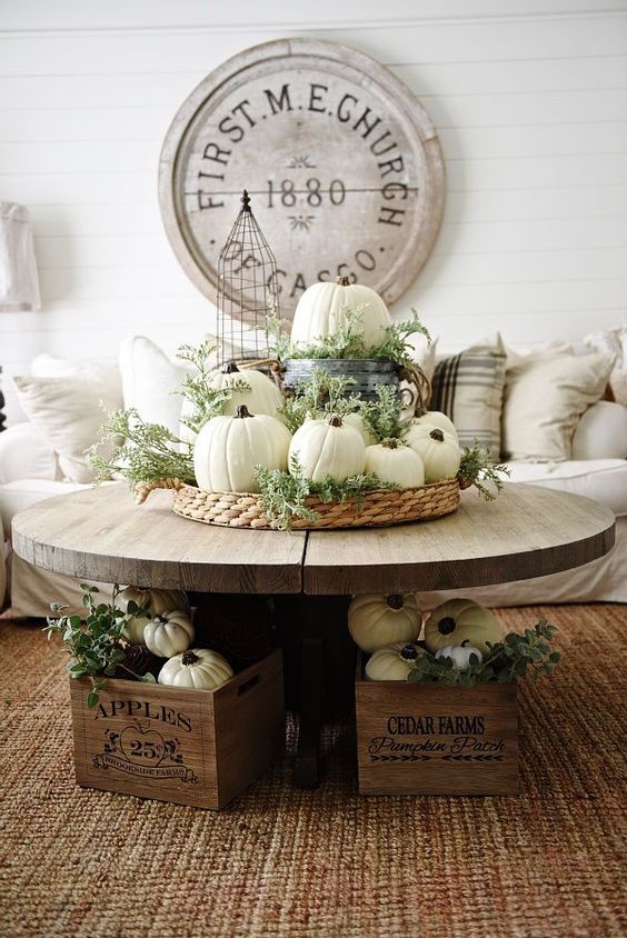 a woven basket with white pumpkins, greenery, a bucket with a pumpkin and crates with them for Thanksgiving and fall
