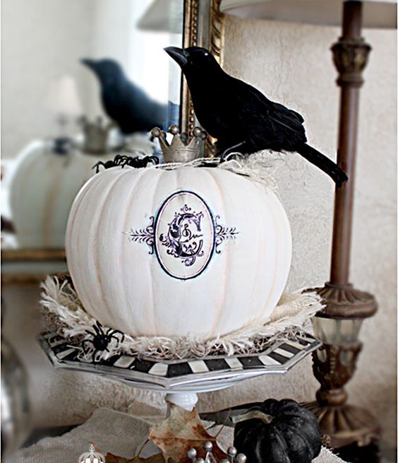 elegant vintage Halloween decor with a black and white stand, a white printed pumpkin with a crown and a black pumpkin and a blackbird