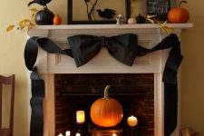 elegant vintage Halloween decor with candles and a pumpkin in the fireplace, a black black bow, blackbirds, pumpkins and leaves