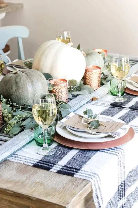 greenery, green and white pumpkins, candleholders, green glasses and greenery on the place settings for Thanksgiving