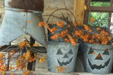 metal buckets with scary faces and lots of branches with berries for easy rustic Halloween decor
