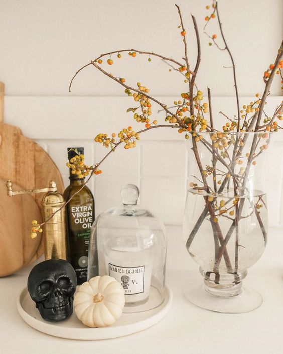 minimalist Halloween decor with branches with berries, a black skull, a white pumpkin is easy to realize and looks cool