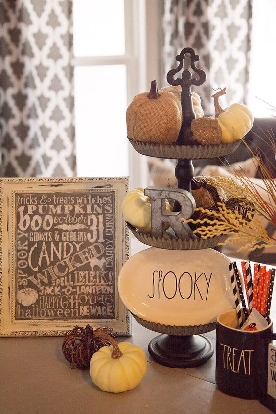 rustic Halloween decor with a metal tiered stand with pumpkins, a plate and a metal letter, pumpkins and a sign