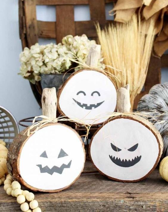 rustic Halloween pumpkins of wood slices with spooky faces, hay and wooden beads for Halloween decor