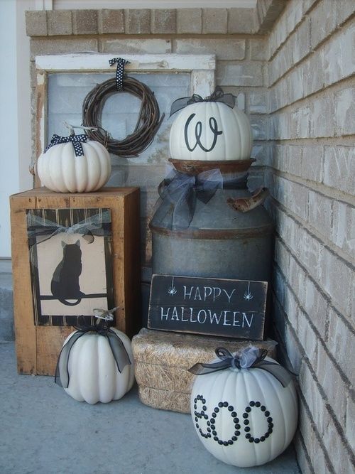 rustic Halloween styling with hay, white pumpkins with black bows, a wooden box with a cat and a vine wreath
