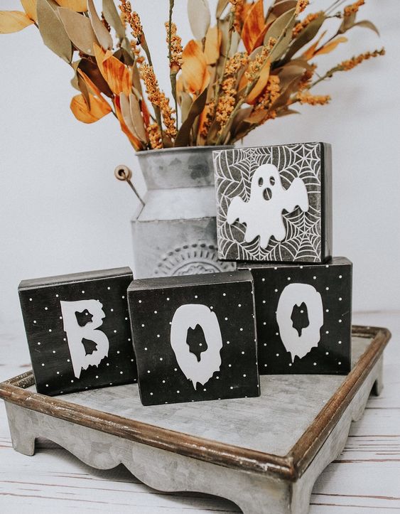 rustic Halloween styling with wooden cube letters, a ghost, a bright dried arrangement in a metal churn