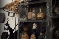 vintage Halloween decor – a black storage unit with vintage potion bottles, spider web, vintage books and skeletons is a chic idea