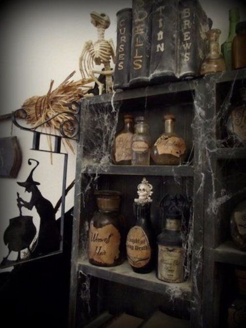 vintage Halloween decor - a black storage unit with vintage potion bottles, spider web, vintage books and skeletons is a chic idea