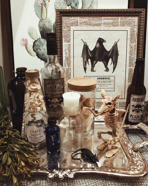 vintage apothecary Halloween decor with a rat skeleton, apothecary bottles, signs and a silver tray is cool and chic