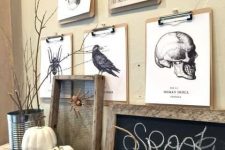 vintage rustic Halloween decor with scary prints and art, a chalkboard piece in a wooden frame a spider, pumpkins, branches and a skeleton