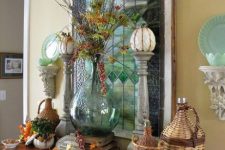 vintage rustic Thanksgiving decor with dried leaves, woven bottles, wooden stands with pumpkins, berries and leaves