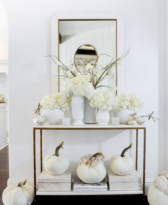 white Thanksgiving decor with fabric pumpkins and feathers, white vases and blooms is a beautiful idea for fall