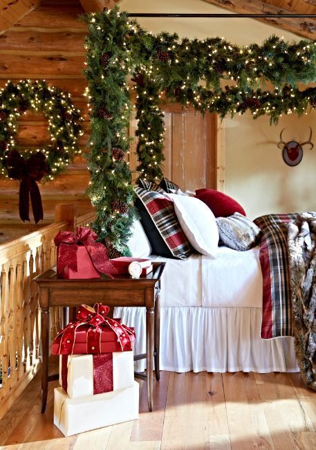 a Christmas bedroom with evergreens, lights, pinecones and large gift boxes that will make you feel very holiday-like
