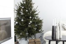 a Christmas tree with silver and clear ornaments and an arrangement of black and white candleholders for a Nordic feel