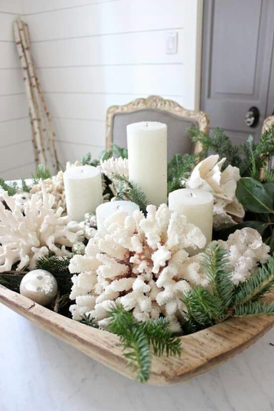 A beach Christmas centerpiece of a wooden bowl, with evergreens, corals, pillar candles, silver and pearl colored ornaments is amazing