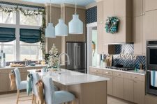 a beach Christmas kitchen with a tabletop Christmas tree, an evergreen and pinecone garland, an evergreen wreath with blue ornaments