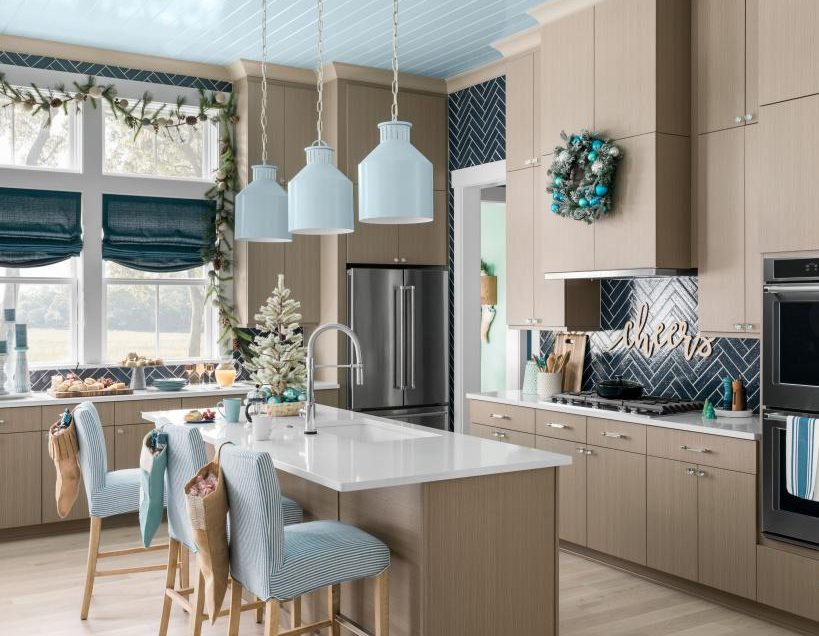 A beach Christmas kitchen with a tabletop Christmas tree, an evergreen and pinecone garland, an evergreen wreath with blue ornaments