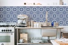 a beautiful and airy industrial kitchen with metal units, a bold blue Moroccan tile backsplash and pendant lamps
