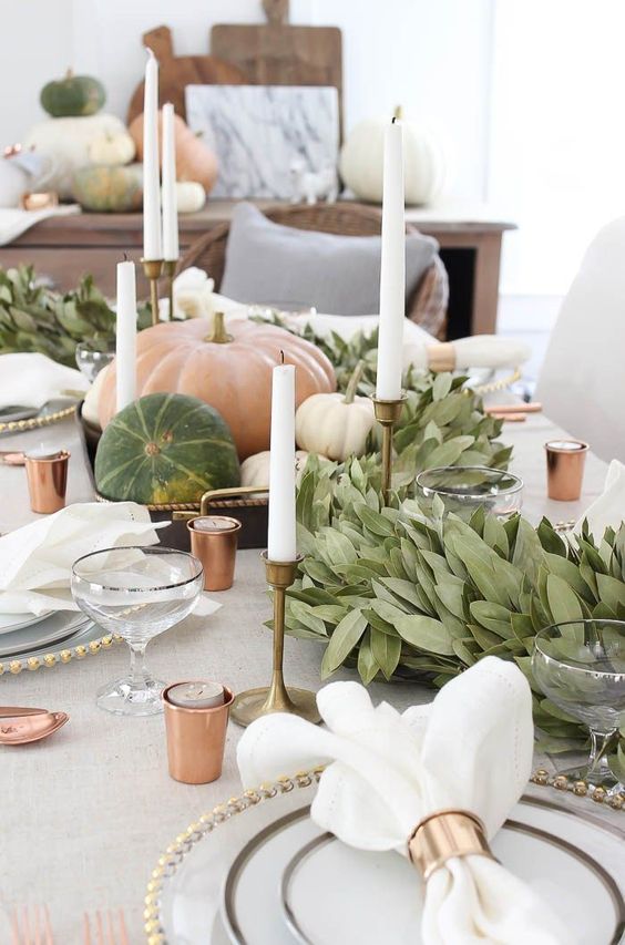 A beautiful natural tablescape with greenery and lots of natural looking pumpkins for Thanksgiving