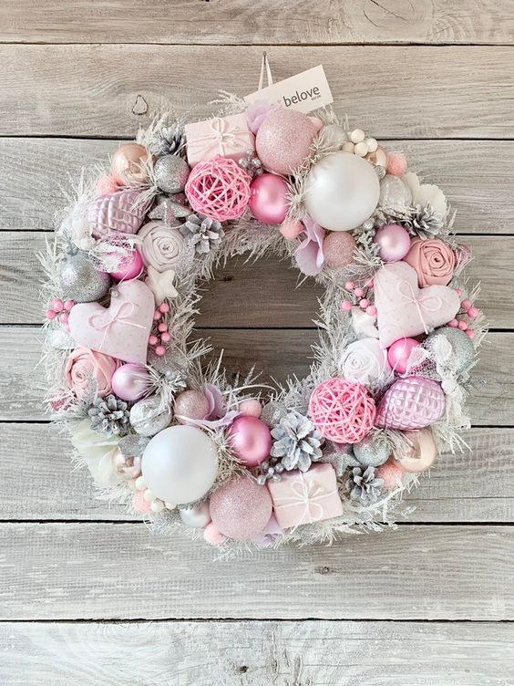 a beautiful pastel pink and silver Christmas wreath with hearts, ornaments, snowy pinecones, fluffs and yarn balls is amazing