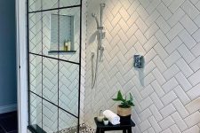 a black and white bathroom with white chevron tiles on the walls, black and white Moroccan tiles on the floor and a glass shower wall