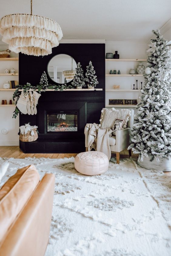 a boho farmhouse Christmas living room with a flocked tree and a cluster of such mini trees on the mantel plus stockings