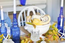 a bold blue and yellow Thanksgiving table setting with blue bottle candleholders and blue printed placemats and napkins
