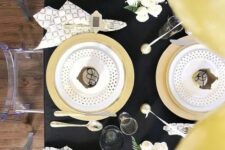 a chic black and gold tablescape with polka dots, geo prints and some white blooms are an amazing combo for NYE