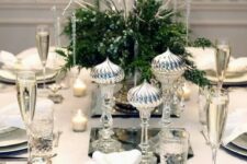 a chic silver-infused table setting with greenery and berries and silver imitating icicles and silver cutlery and chargers
