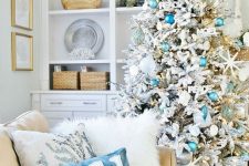 a coastal Christmas space with a flocked Christmas tree with mint, blue ornaments, starfish, lights and corals and a duo of lovely beach-inspired pillows