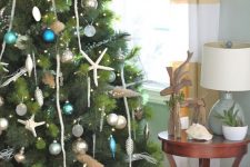 a coastal Christmas tree with lights, starfish, driftwood, blue, teal, green and silver ornaments is a gorgeous and refined idea
