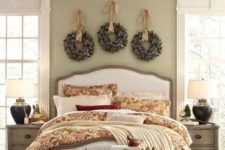 a cozy Christmas bedroom with snowy evergreen wreaths over the bed, candle lanterns, a basket chest with storage