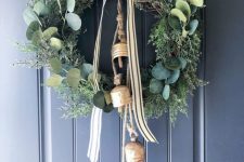 a greenery and foliage Christmas wreath with a striped bow and large vintage bells is a lovely and chic decoration
