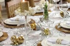 a holiday tablescape with gold and silver ornaments, wicker chargers, glitter candles and white blooms