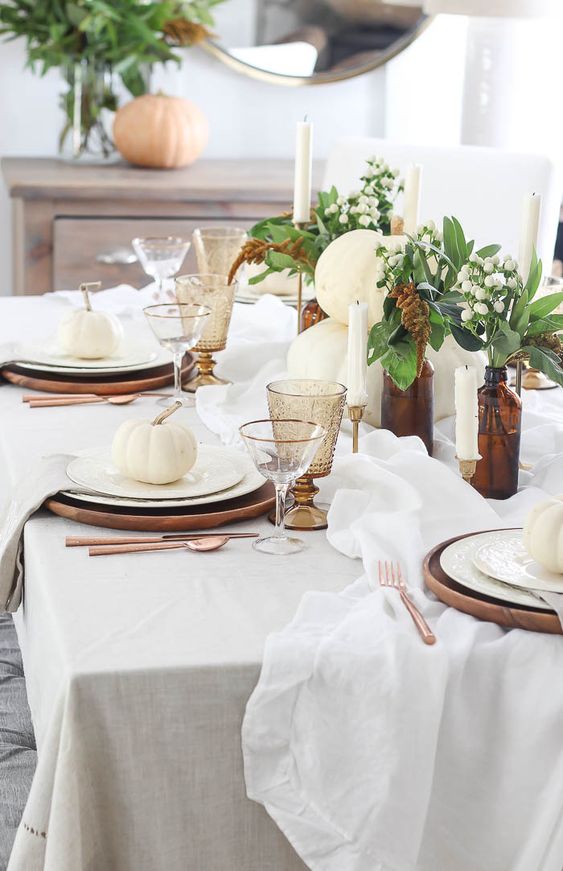 a lovely and fresh Thanksgiving tablescape with white pumpkins, lily of the valley, candles and white linens