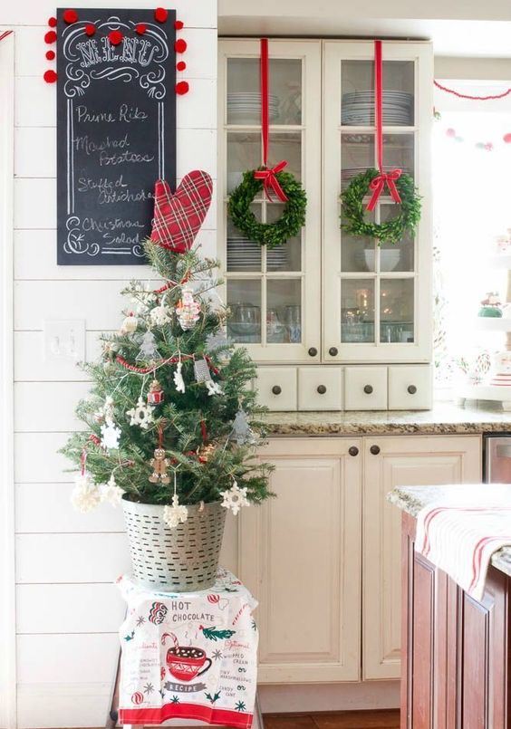 a mini Christmas tree with ornaments, a red heart and berry garlands plus evergreen wreaths with red ribbons