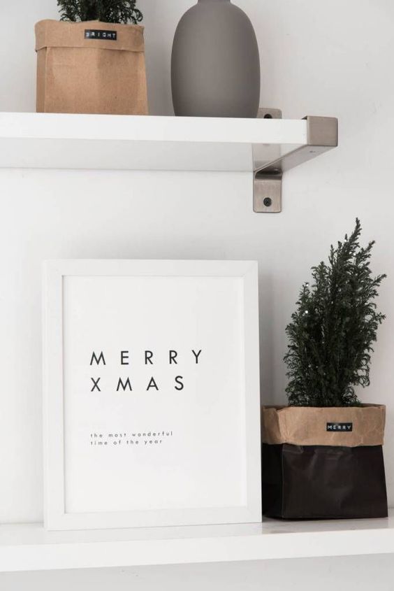 a minimalist Christmas artwork and a potted Christmas tree in a paper bag