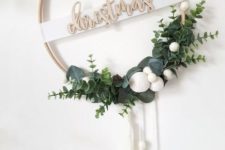 a minimalist Christmas wreath of an embroidery hoop, greenery, white pompoms and white tassels