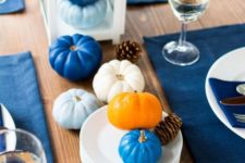 a modern Thanksgiving tablescape with bold blue placemats and light and bold blue pumpkins is a chic idea