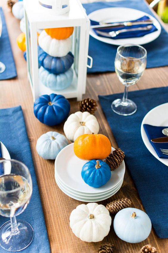 a modern Thanksgiving tablescape with bold blue placemats and light and bold blue pumpkins is a chic idea