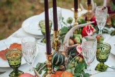a natural Thanksgiving table runner of greenery, antlers, pumpkins and pomegranates plsu burgundy candles