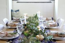 a navy and white table runner with pearls, napkins with blue edges and lots of fresh greenery for a modern and simple tablescape