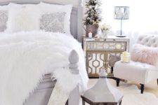 a neutral Christmas bedroom with a snowy mini tree, an evergren wreath with skis, a stocking, an oversized lantern and a faux fur blanket