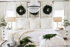 a neutral shabby chic Christmas bedroom with evergreen wreaths, garlands, knit blankets and mini Christmas trees