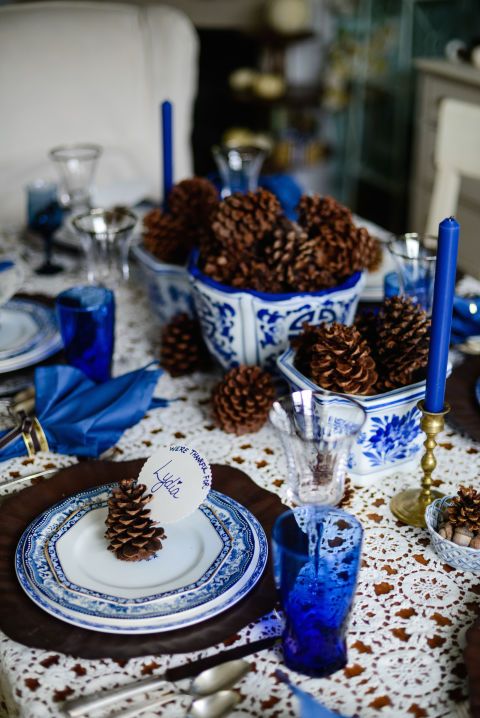 a non-typical Thanksgiving tablescape with bold blue glasses, napkins, candles and porcelain looks jaw-dropping